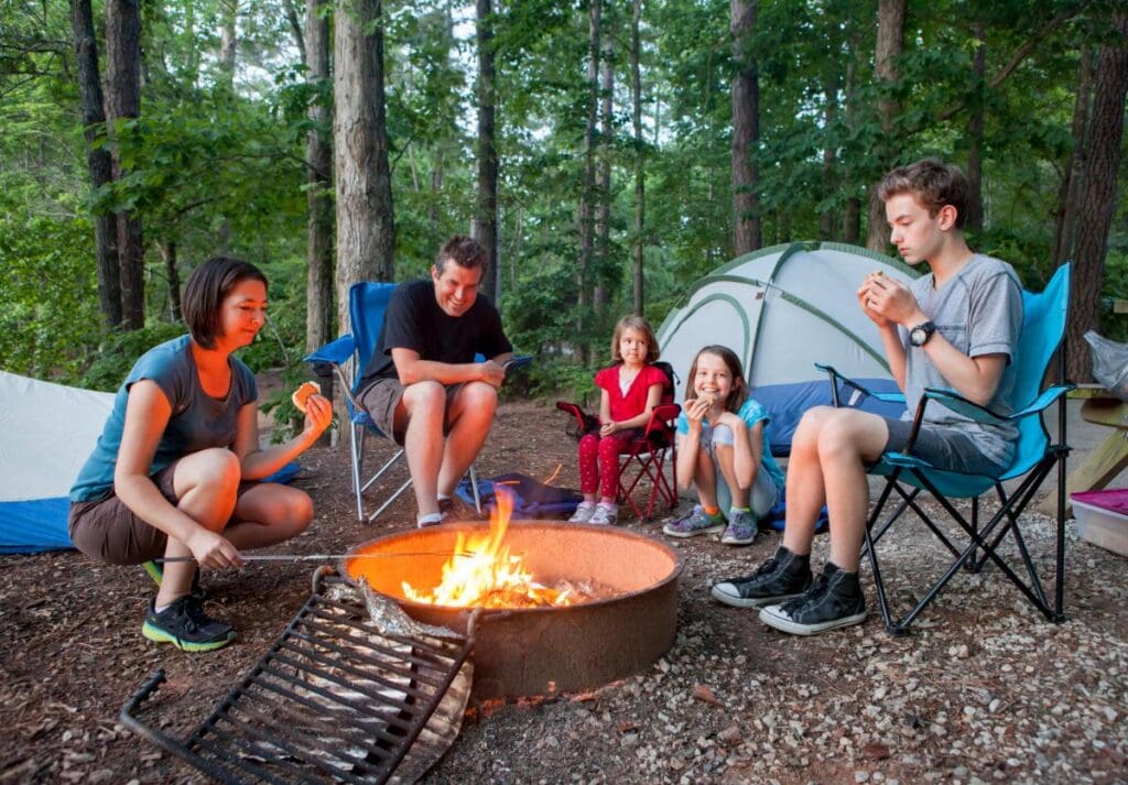 family gathered around fire pit while camping