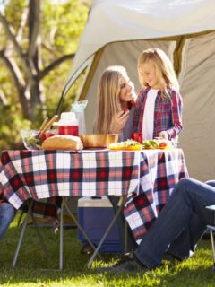 family sitting at table eating while camping