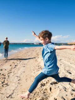 kid running on beach with family in background
