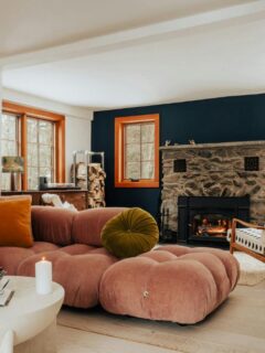 Modern lounge with a curved pink sofa, patterned chair, and stone fireplace