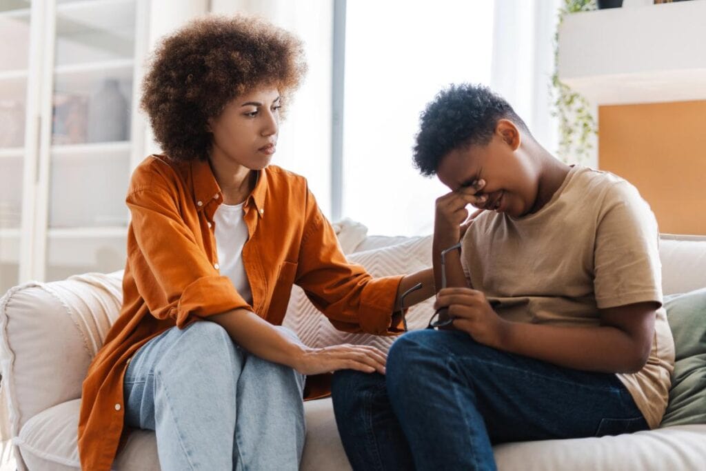 mother sitting on couch comforting her child
