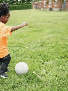 toddler playing soccer with parent