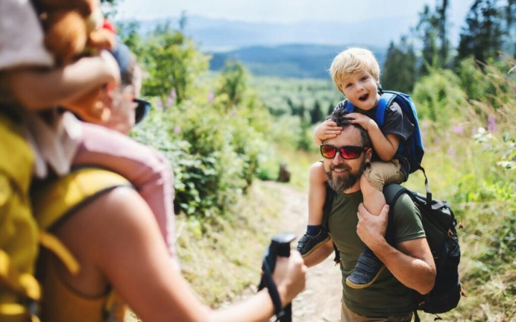 toddler on dad's shoulders during a hike