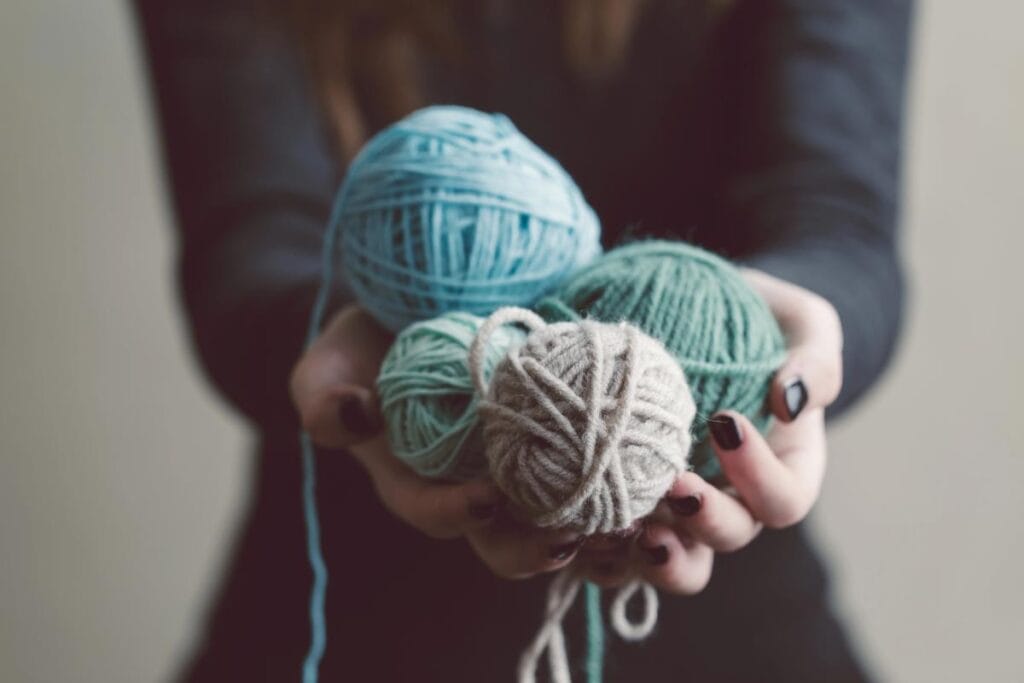 woman holding four balls of yarn