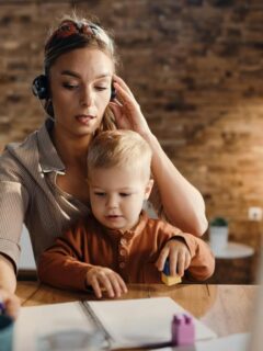 mom working and talking on headset while holding baby