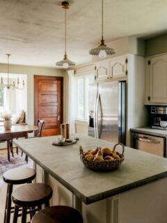 Bright kitchen with a central island, vintage-style pendants, dining nook, and large windows.