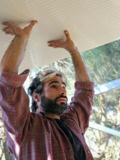 man installing white roof on outdoor structure