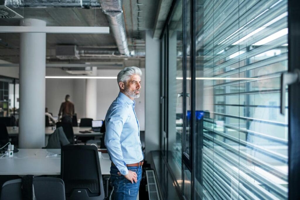 man looking through windows with louvre panels