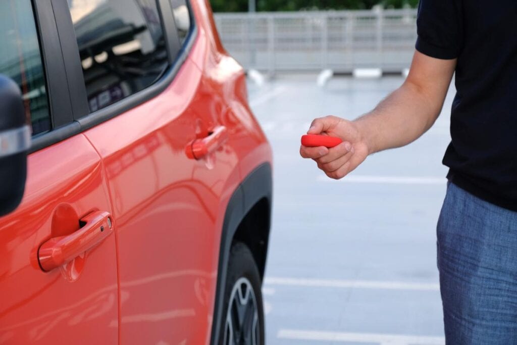 man unlocking red rental car