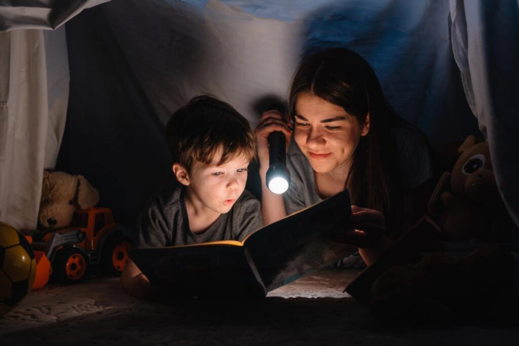 mom and son reading together during a storm using a flashlight