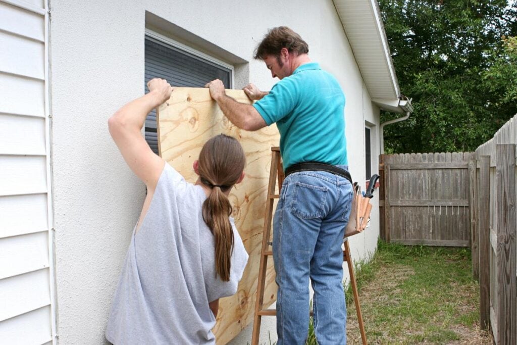 two men boarding up windows before a hurricane