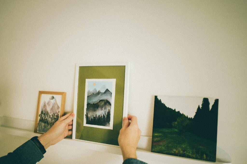 person placing framed photo on mantel