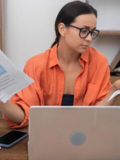 Woman reviewing utility bills and household expenses at a laptop.